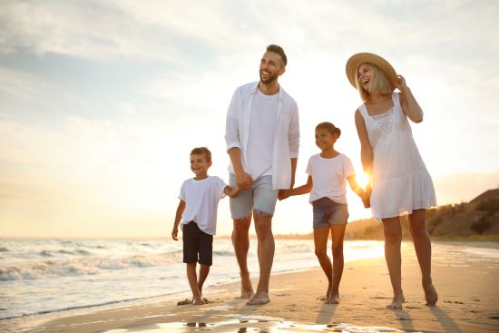 happy couple walking on beach with kids