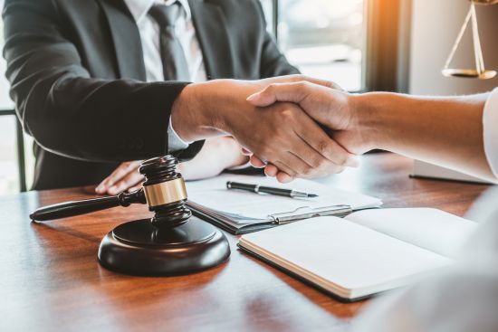 Handshake with a gavel, symbolizing a structured settlement agreement.