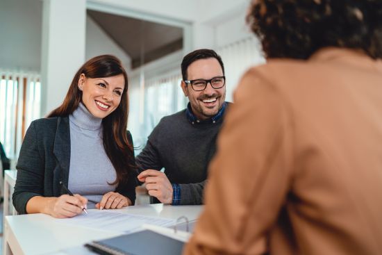 Smiling couple meeting with a professional advisor, discussing the process of selling their structured settlement.