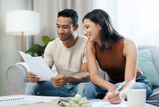 A smiling couple reviewing structured settlement documents in a cozy living room.