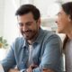 A cheerful couple working on a laptop, researching structured settlement buyers at home.