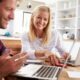 A cheerful couple discussing options to sell annuity payments while using laptops at a kitchen table.